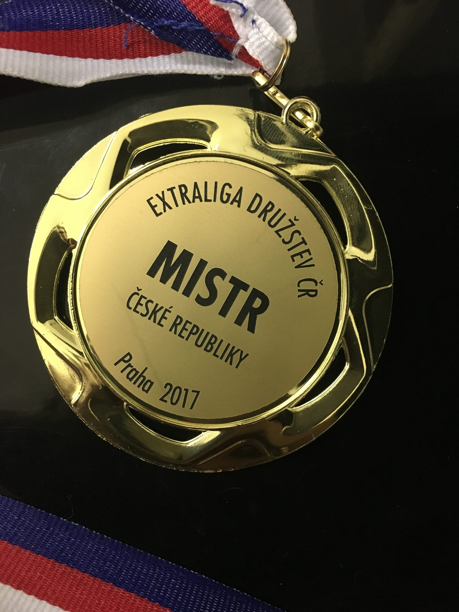 Zlatá medaile s nápisem Extraliga družstev ČR, Mistr České republiky, Praha 2017, na trikolóře
