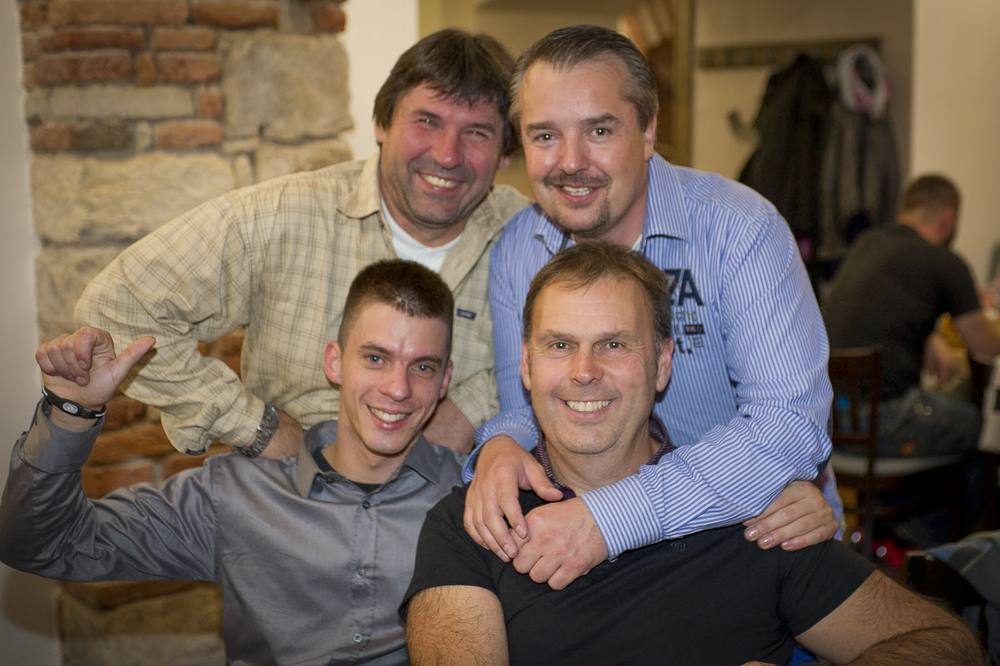Čtyři muži se usmívají při společné fotografii v restauraci